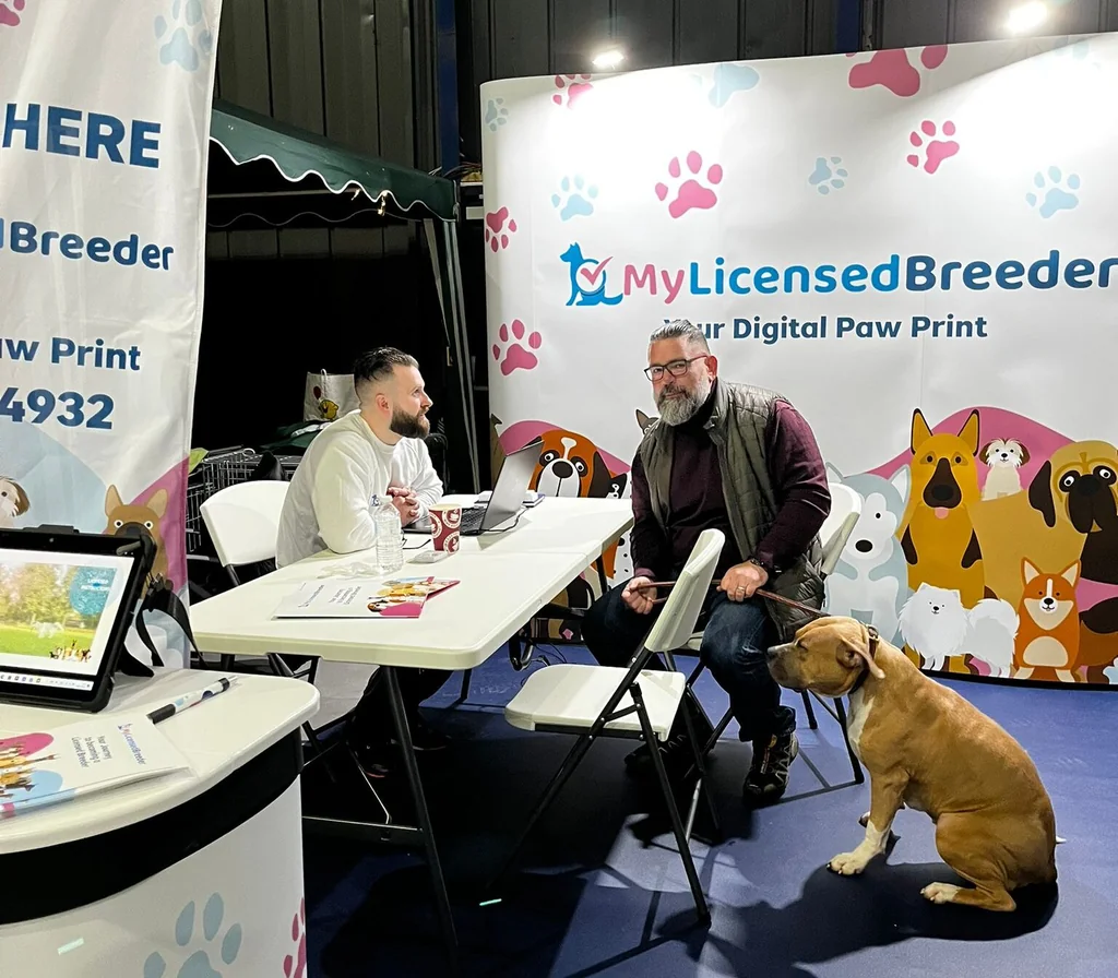 A conversation at the My Licensed Breeder stand with a dog beside the visitor